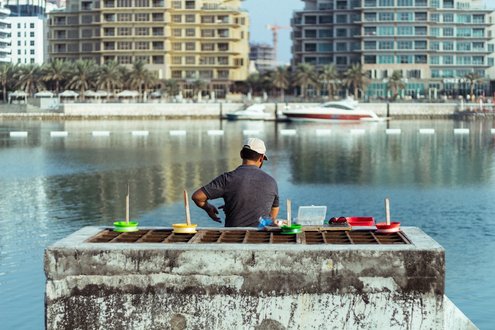 homme en chemise bleue assis sur le quai en bois brun pendant la journée