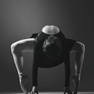 woman in black tank top and black pants bending her body