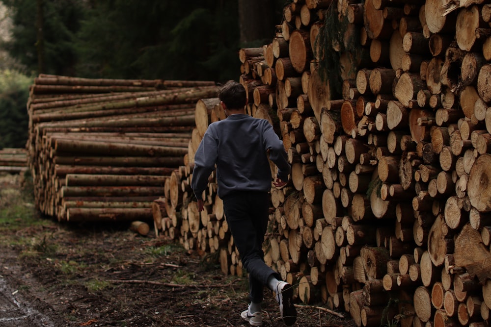 man in black jacket and black pants standing on wood logs