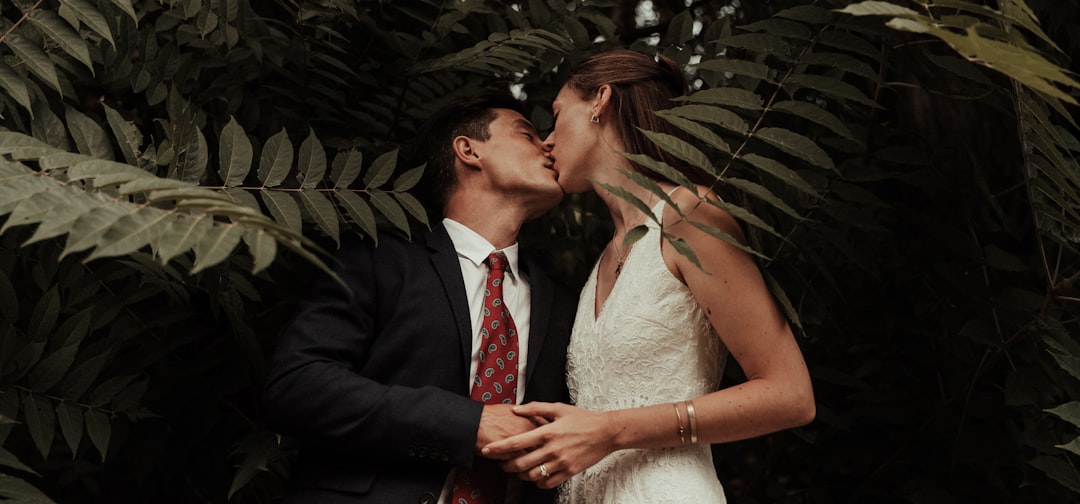 man in black suit kissing woman in white wedding dress