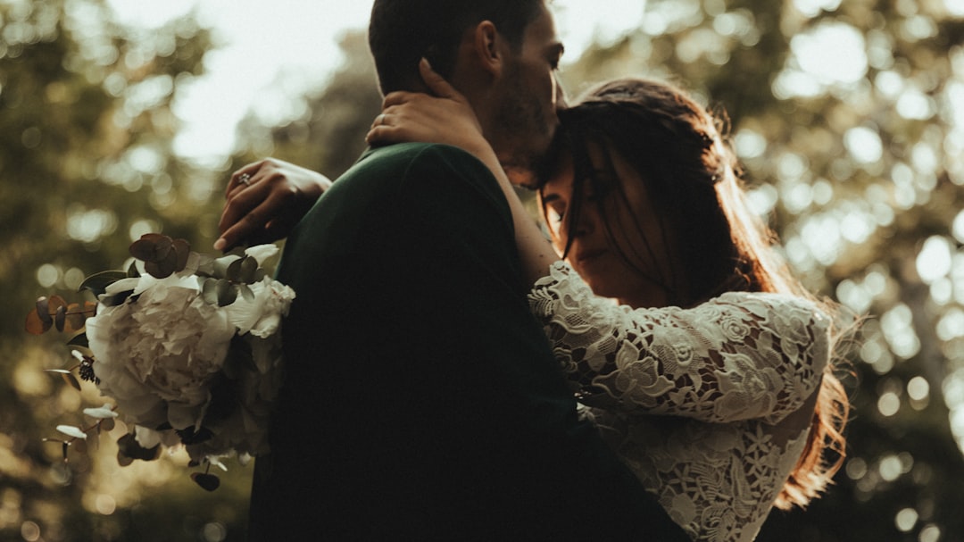 man in black suit kissing woman in white floral dress