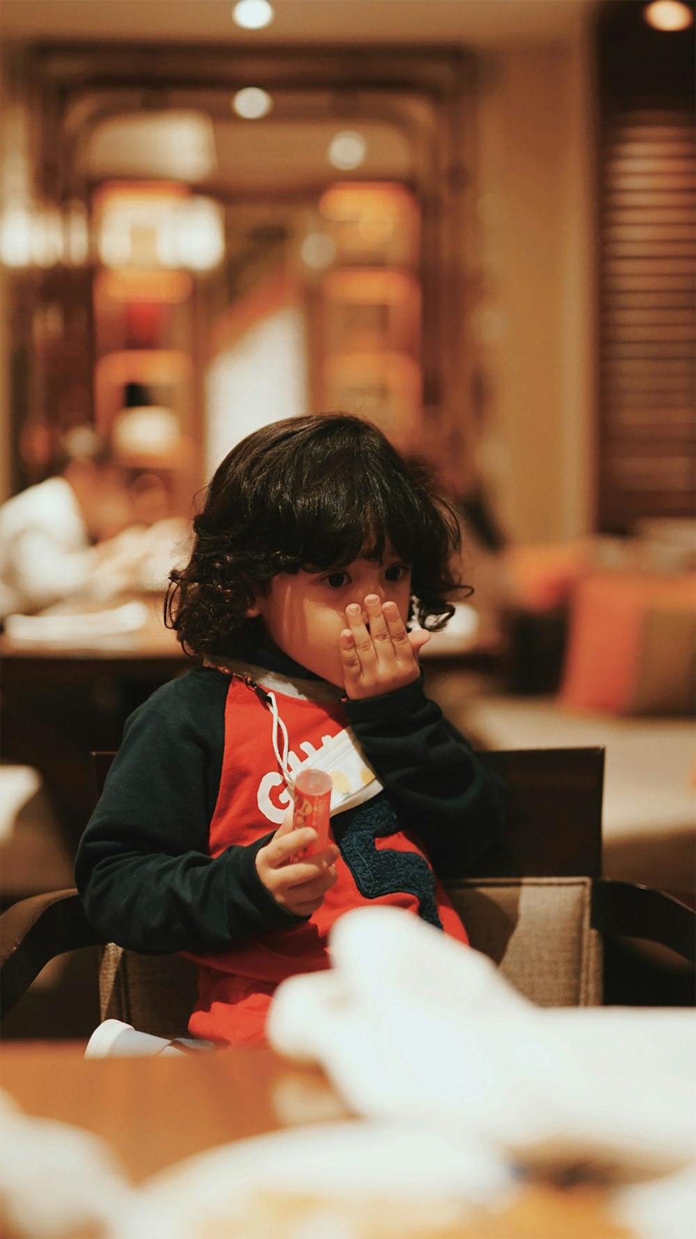 boy in black and red hoodie sitting on brown wooden chair