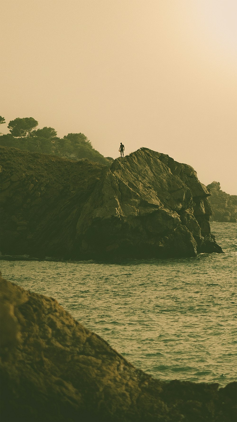 person standing on rock formation near body of water during daytime