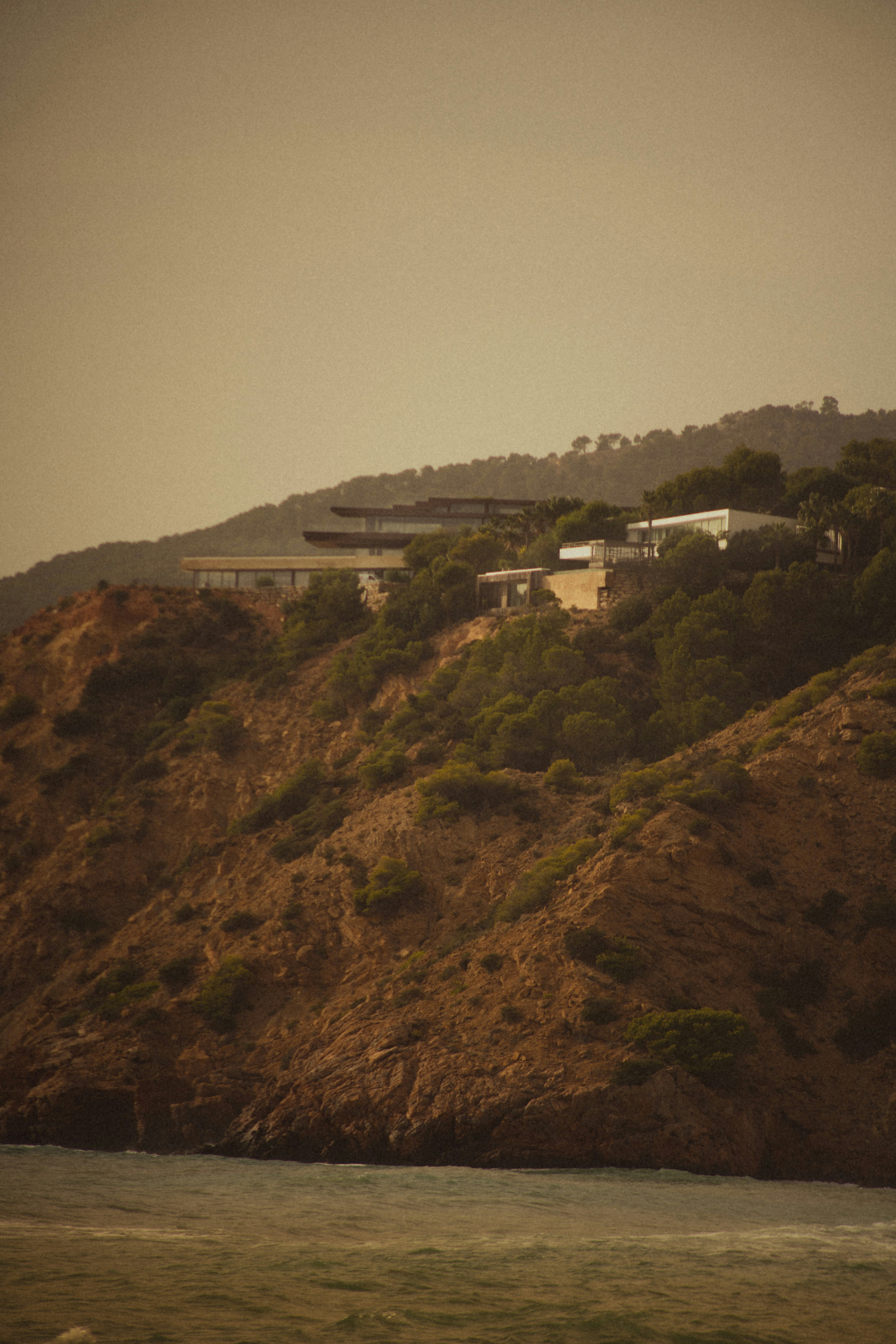white concrete building on brown hill