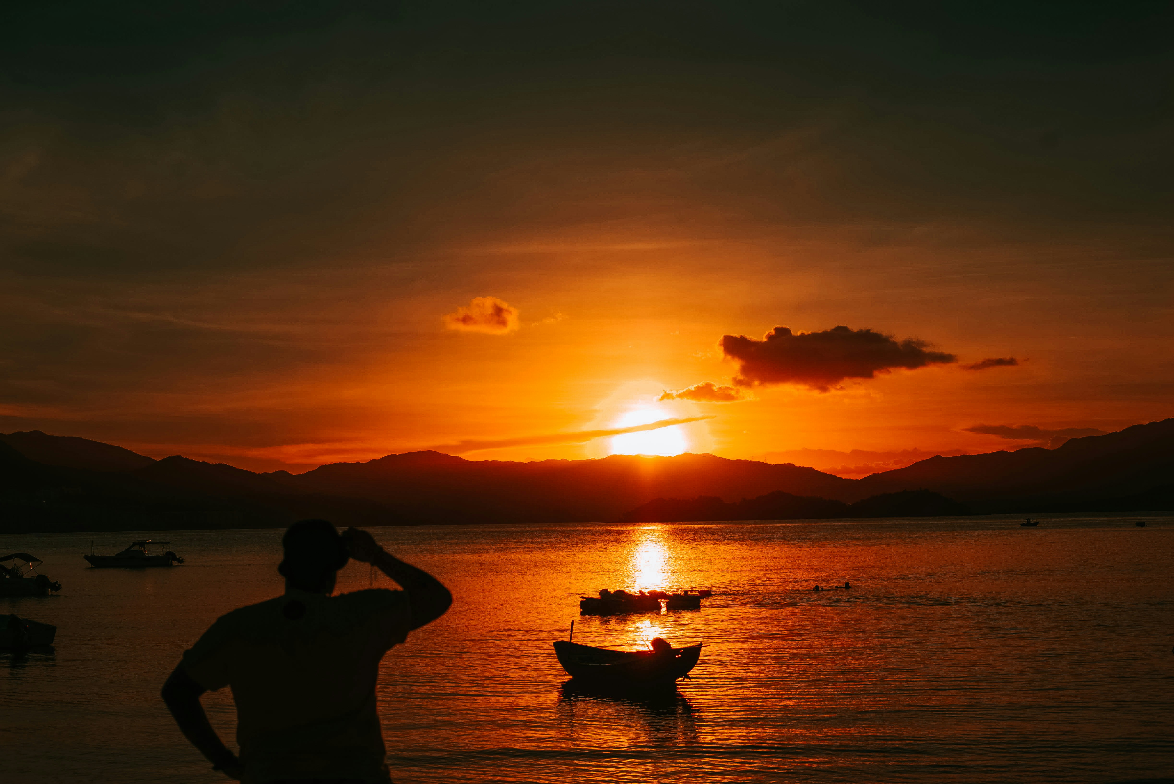 silhouette of man and woman standing on sea shore during sunset