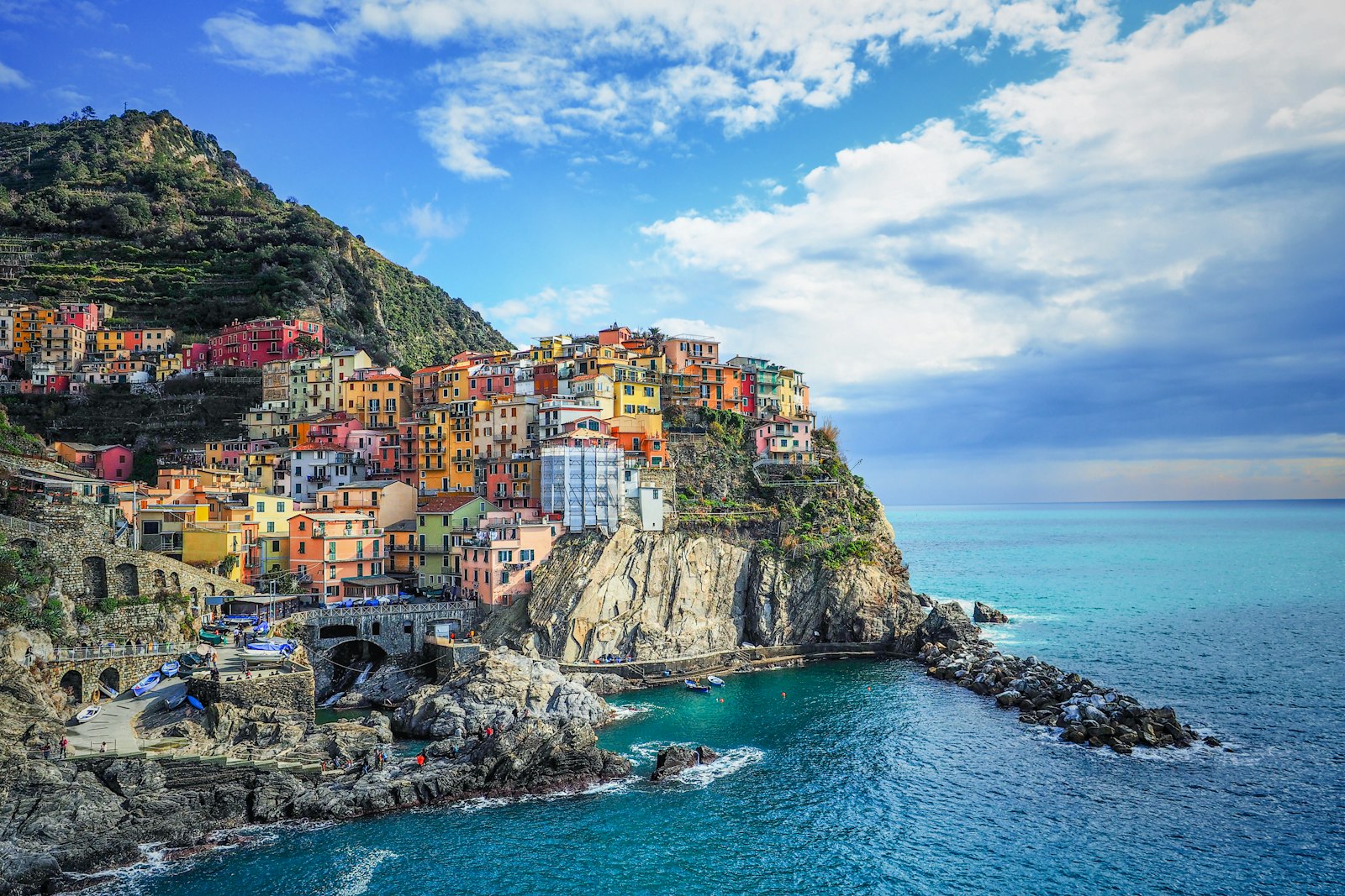 Pastel houses of Manarola perched on a rocky headland above the blue Ligurian Sea in the Cinque Terre