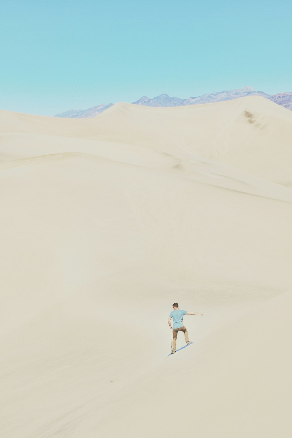 Frau in weißem Hemd und blauen Jeansshorts geht tagsüber auf Sand