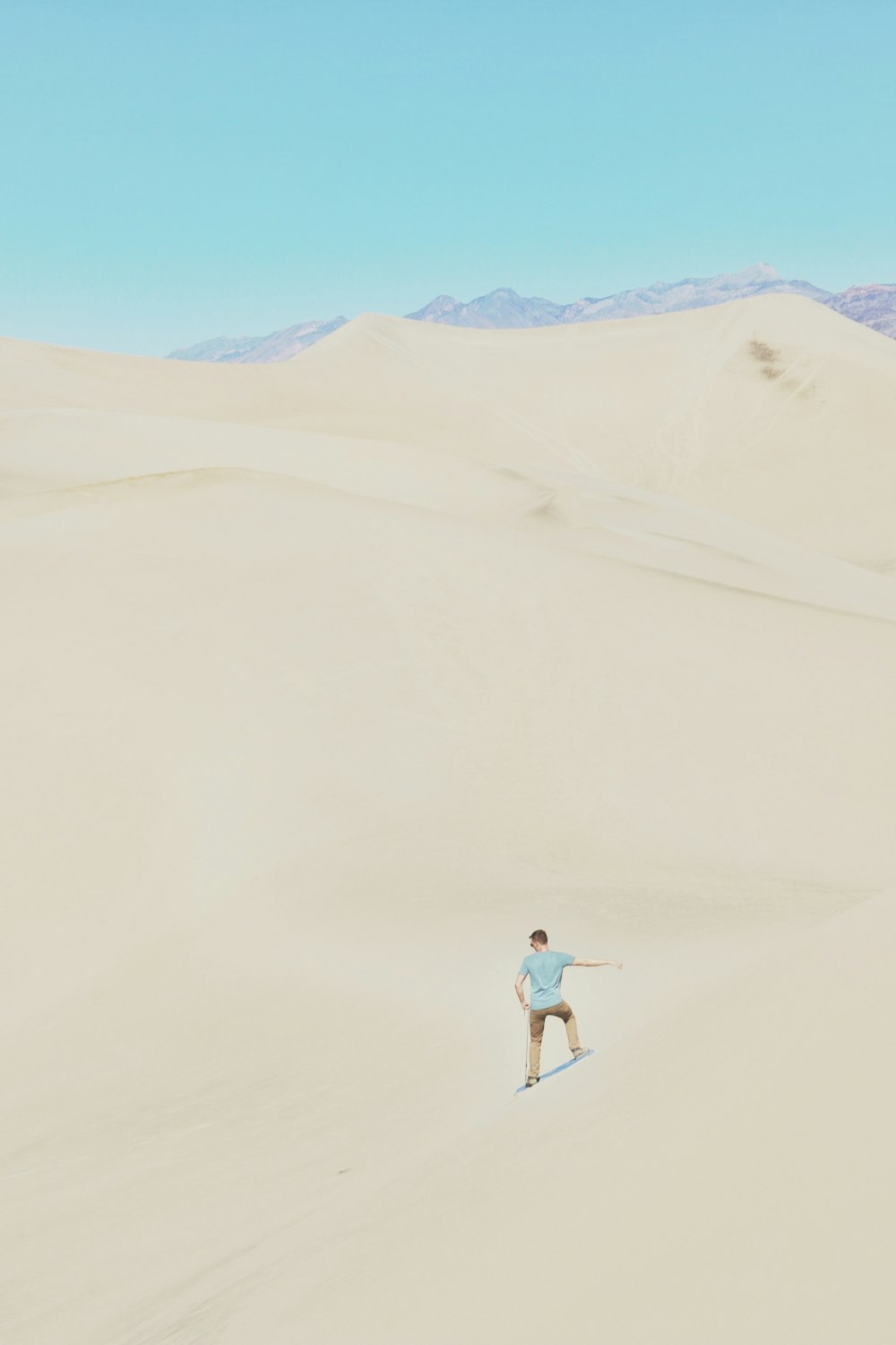 femme en chemise blanche et short en jean bleu marchant sur le sable pendant la journée