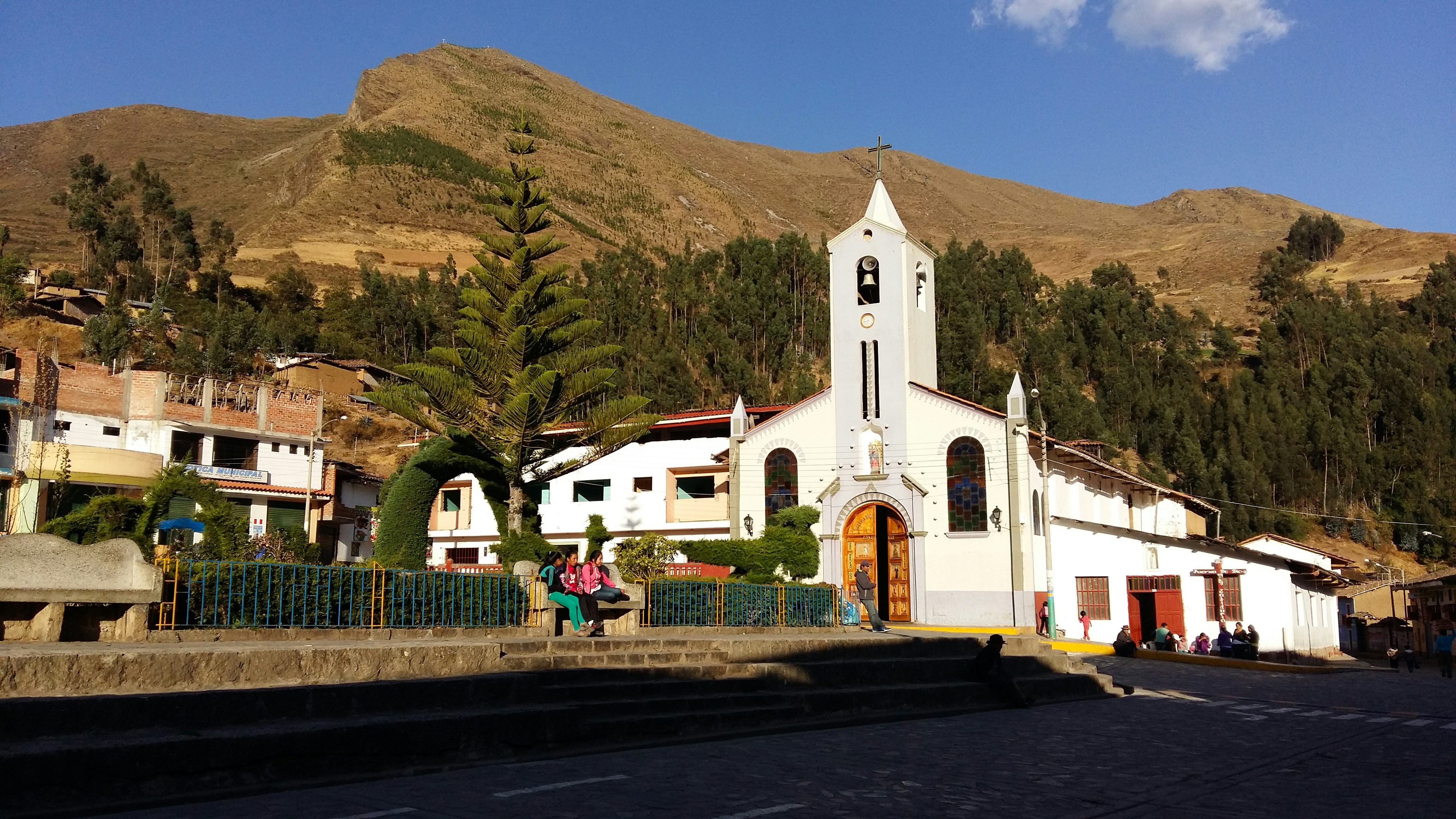 white and brown concrete building near green mountain during daytime