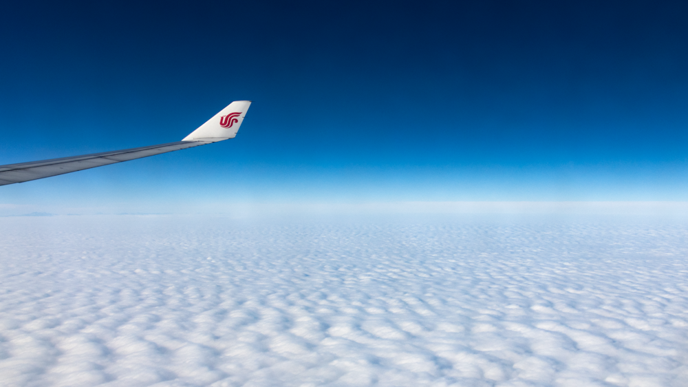 white and red airplane flying over the clouds during daytime