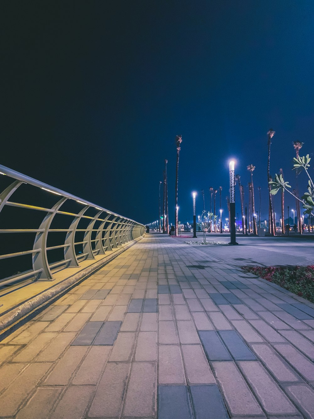 gray concrete pathway with gray metal railings during night time
