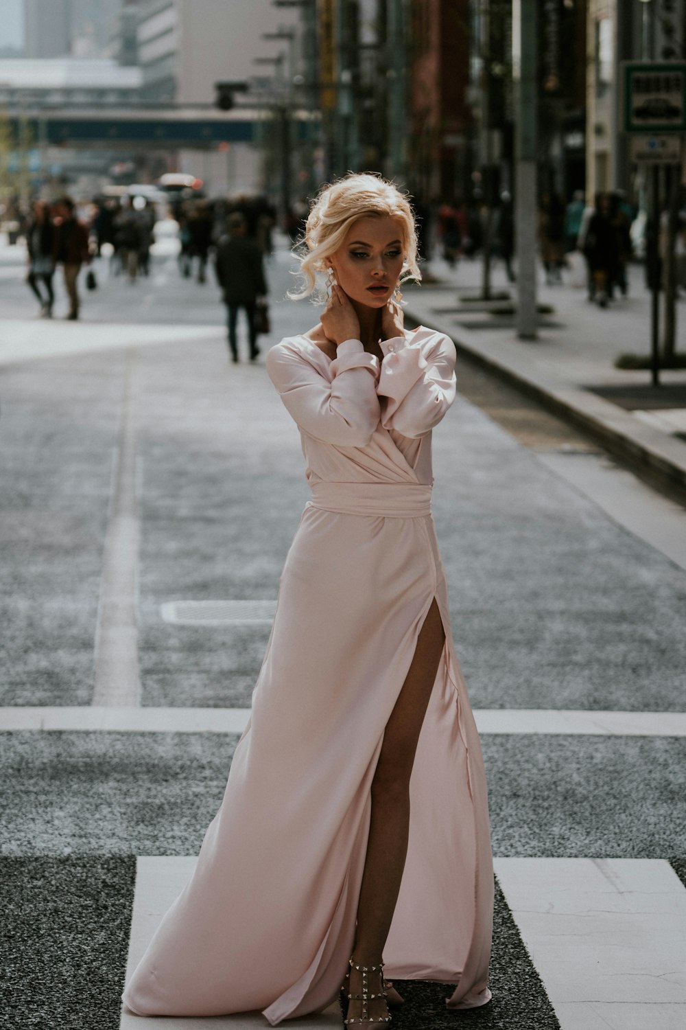 Femme en robe rose à manches longues debout sur la route pendant la journée