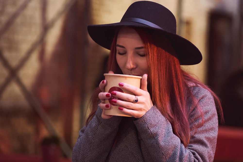 Frau mit schwarzem Hut mit weißem Keramikbecher