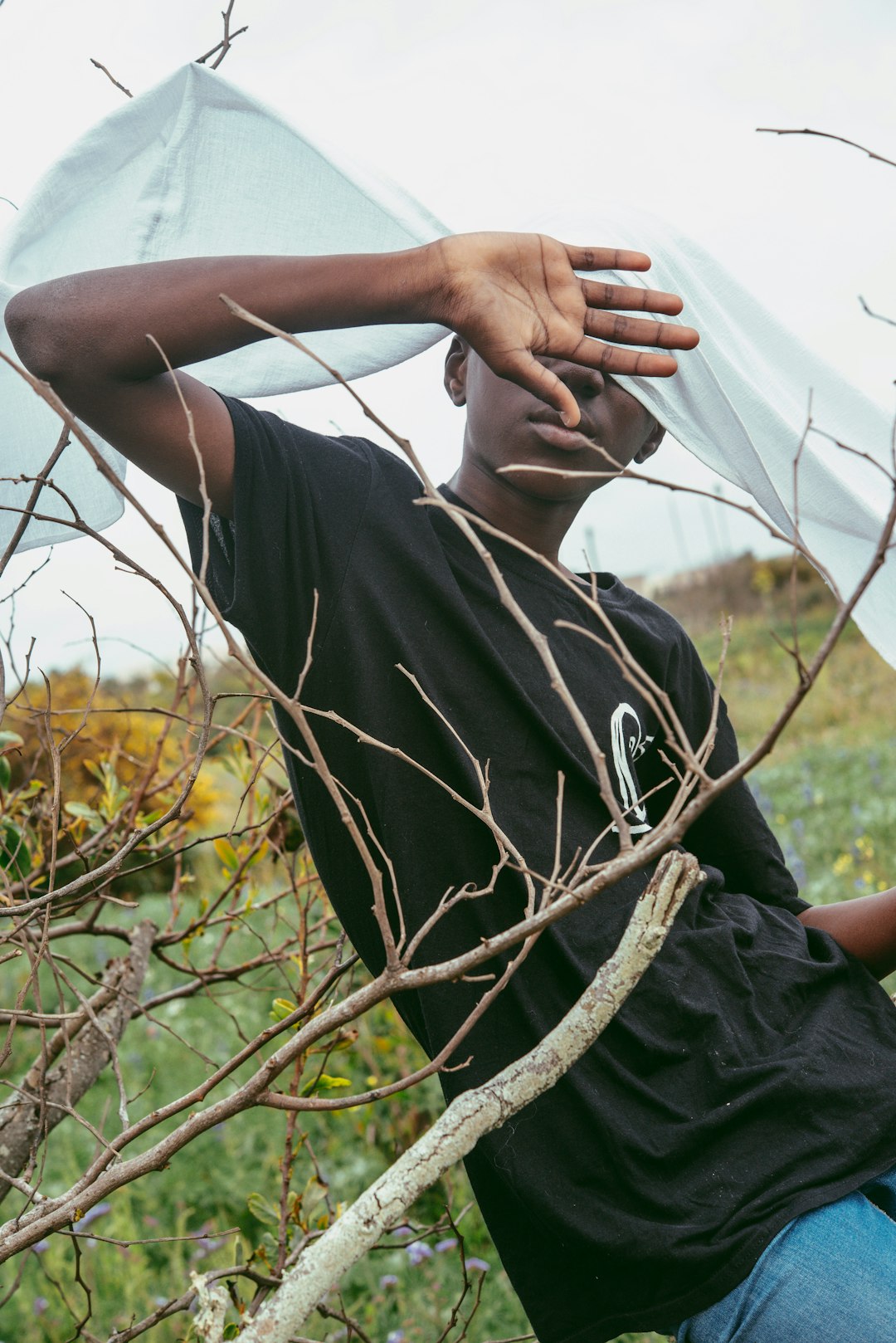 man in black crew neck t-shirt sitting on brown tree branch during daytime