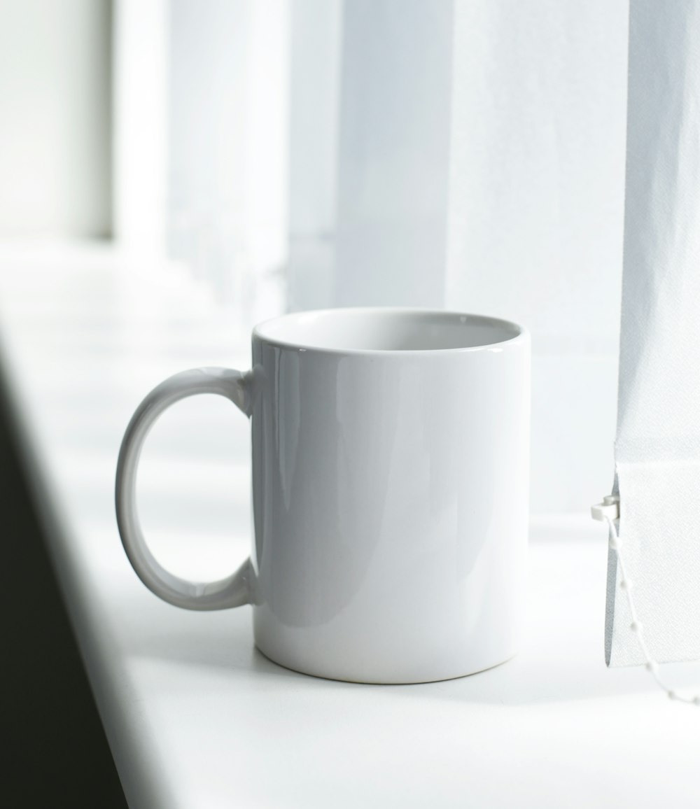 white ceramic mug on white table