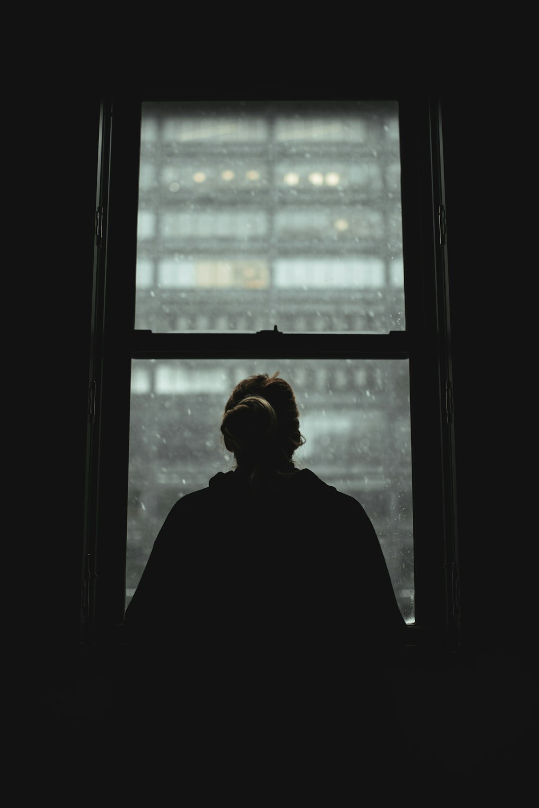 man in black jacket standing near window