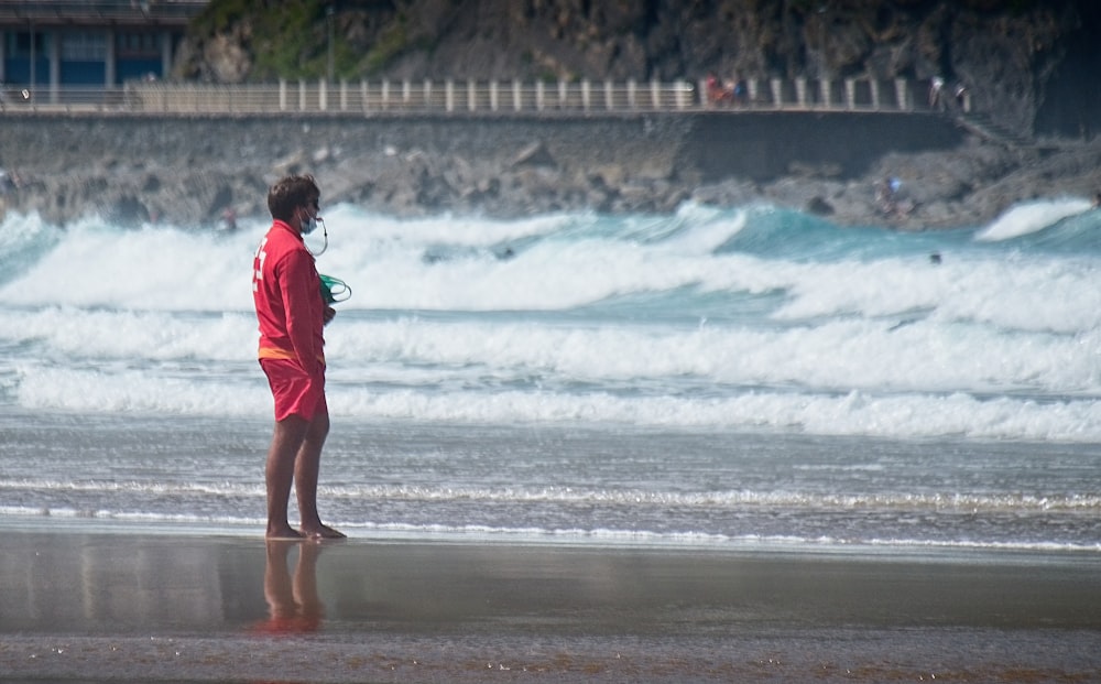 昼間の海岸を歩く赤いシャツの女の子