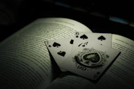 The Ace of Wands card resting beside an open book of tarot, pages glowing with soft candlelight.
