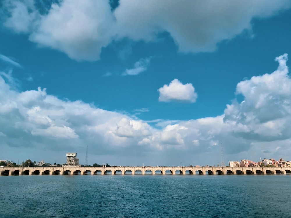 white concrete bridge over body of water under blue sky and white clouds during daytime