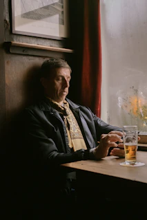 man in black jacket sitting beside brown wooden table