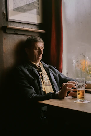 man in black jacket sitting beside brown wooden table