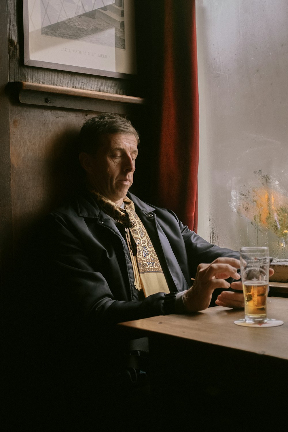 man in black jacket sitting beside brown wooden table