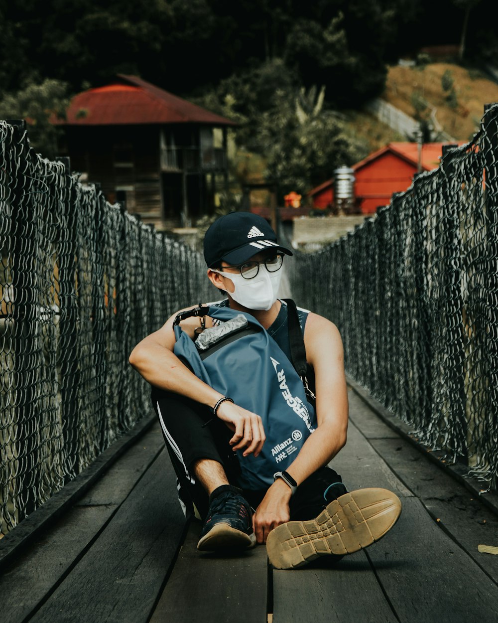 woman in black tank top and black pants sitting on brown wooden bridge during daytime