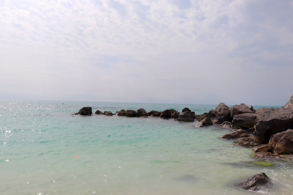 gray rocks on sea under white sky during daytime