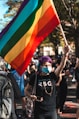 man in black crew neck t-shirt holding a pride flag