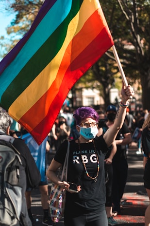 man in black crew neck t-shirt holding a pride flag