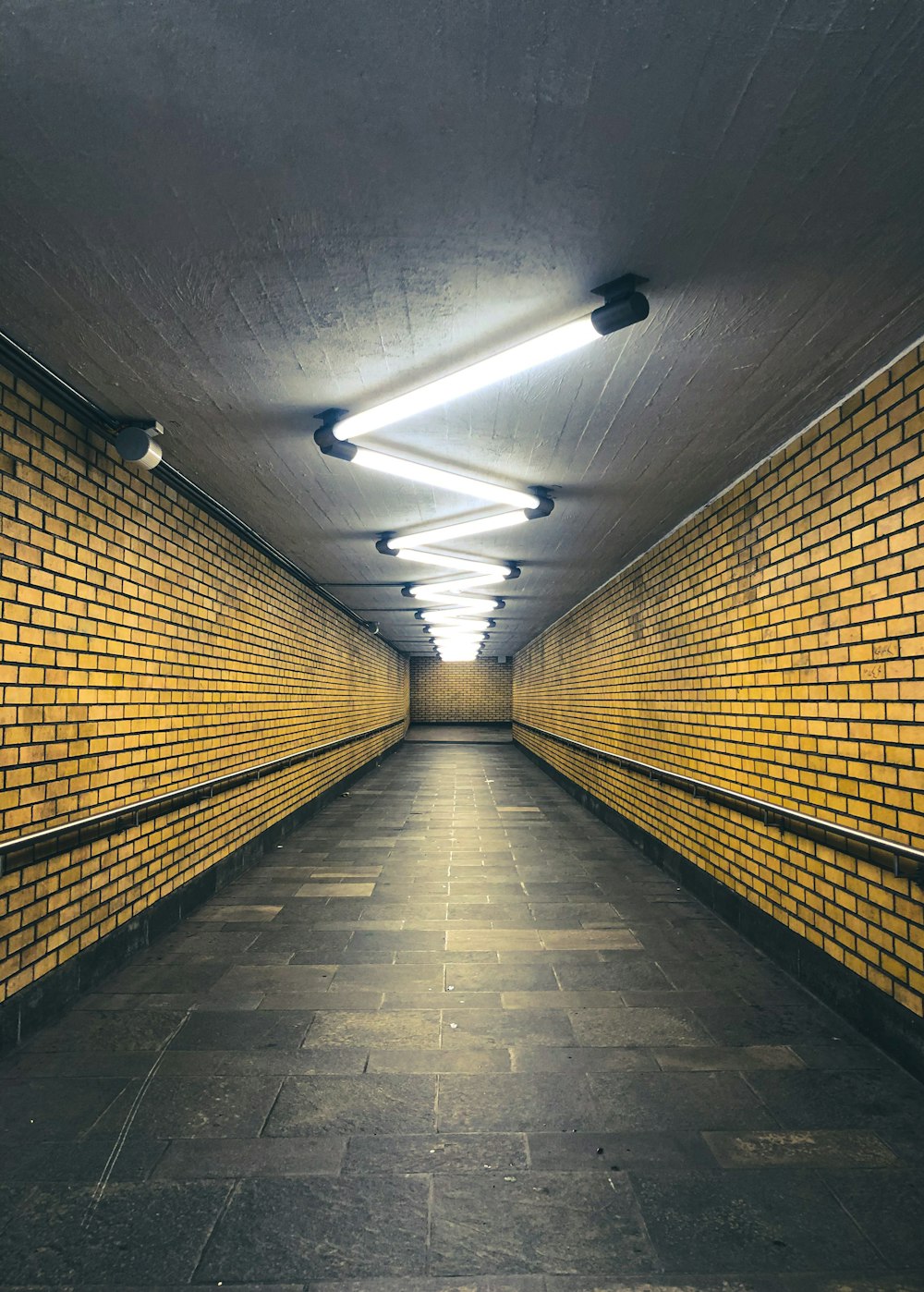 Túnel marrón y negro con luces encendidas durante el día