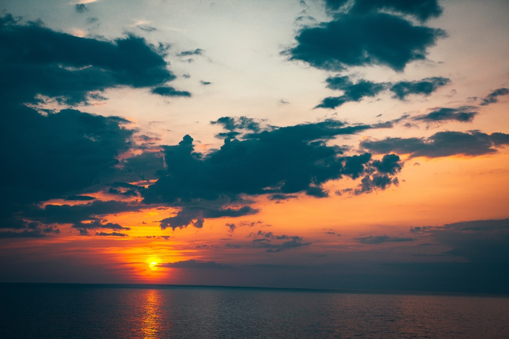 body of water under cloudy sky during sunset