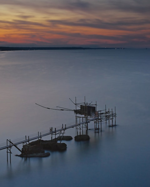 brown wooden dock on body of water during sunset