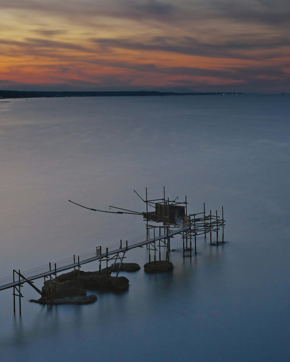 brown wooden dock on body of water during sunset