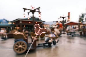 Classic Mickey-shaped treat held up against a backdrop of Main Street’s vibrant stores
