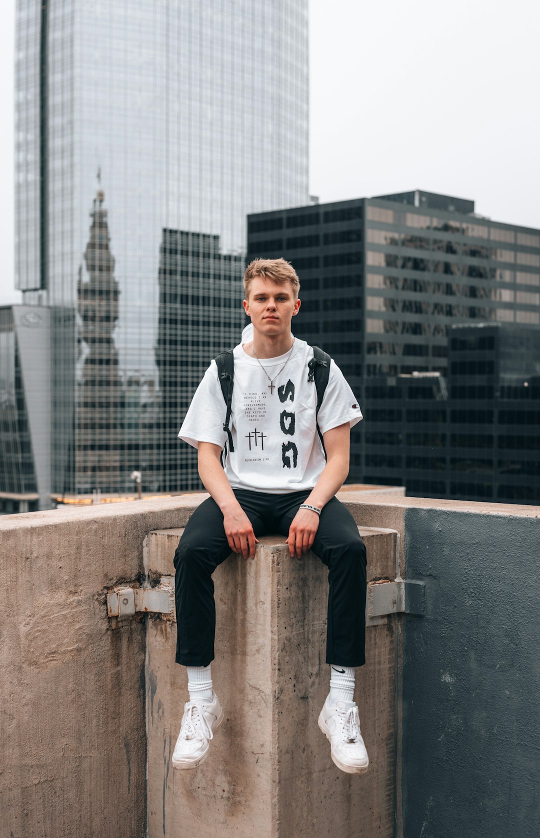 man in white crew neck t-shirt sitting on brown concrete bench during daytime