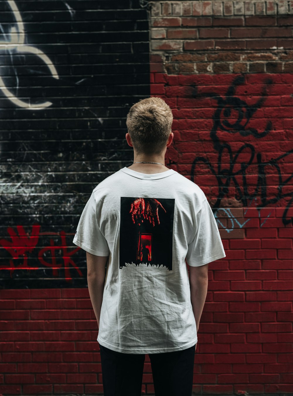 Man in white crew neck t-shirt standing beside brick wall photo – Free Grey  Image on Unsplash