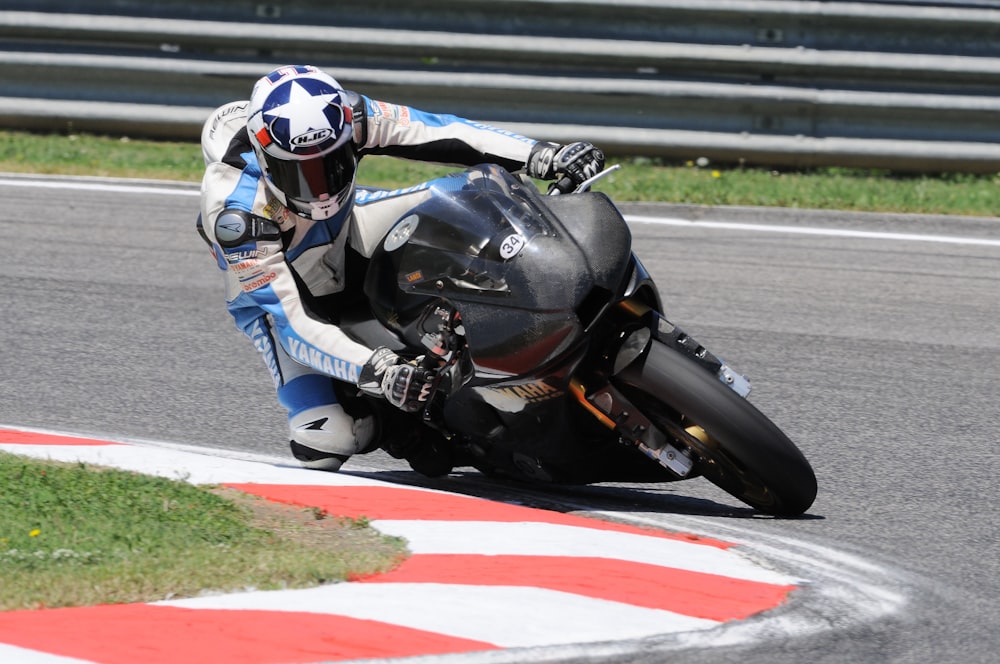 homem no terno azul e branco da motocicleta andando na motocicleta