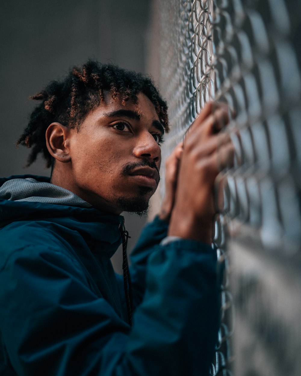 man in blue jacket standing near gray metal fence