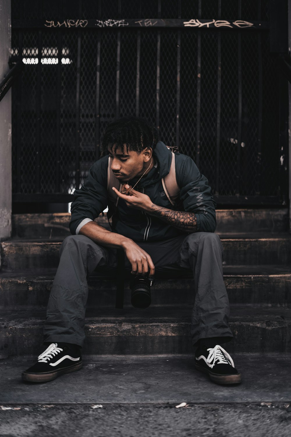 man in black long sleeve shirt and blue denim jeans sitting on stairs