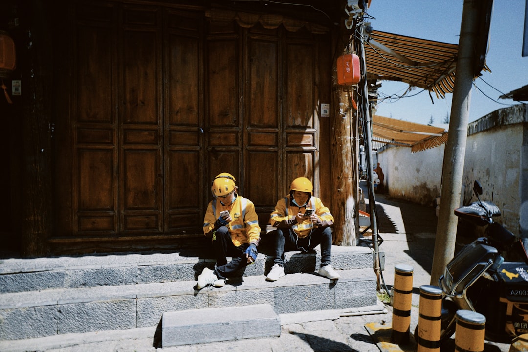 2 men in black and yellow jacket sitting on concrete bench