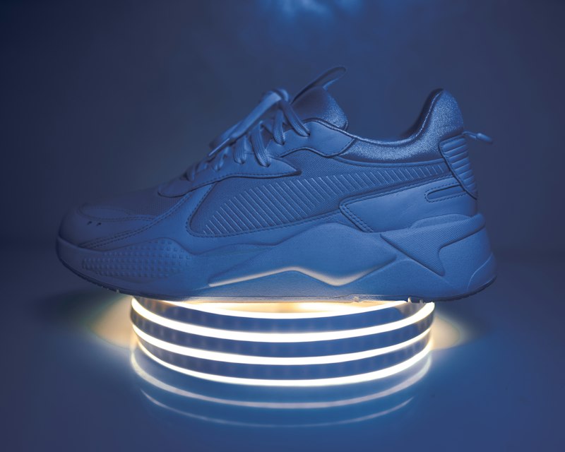 Đôi giày sneaker chụp nghệ thuật từ góc 3/4 trên nền gradient
