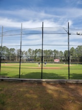 A coach attentively guiding a young baseball player through batting practice on a sunny field.
