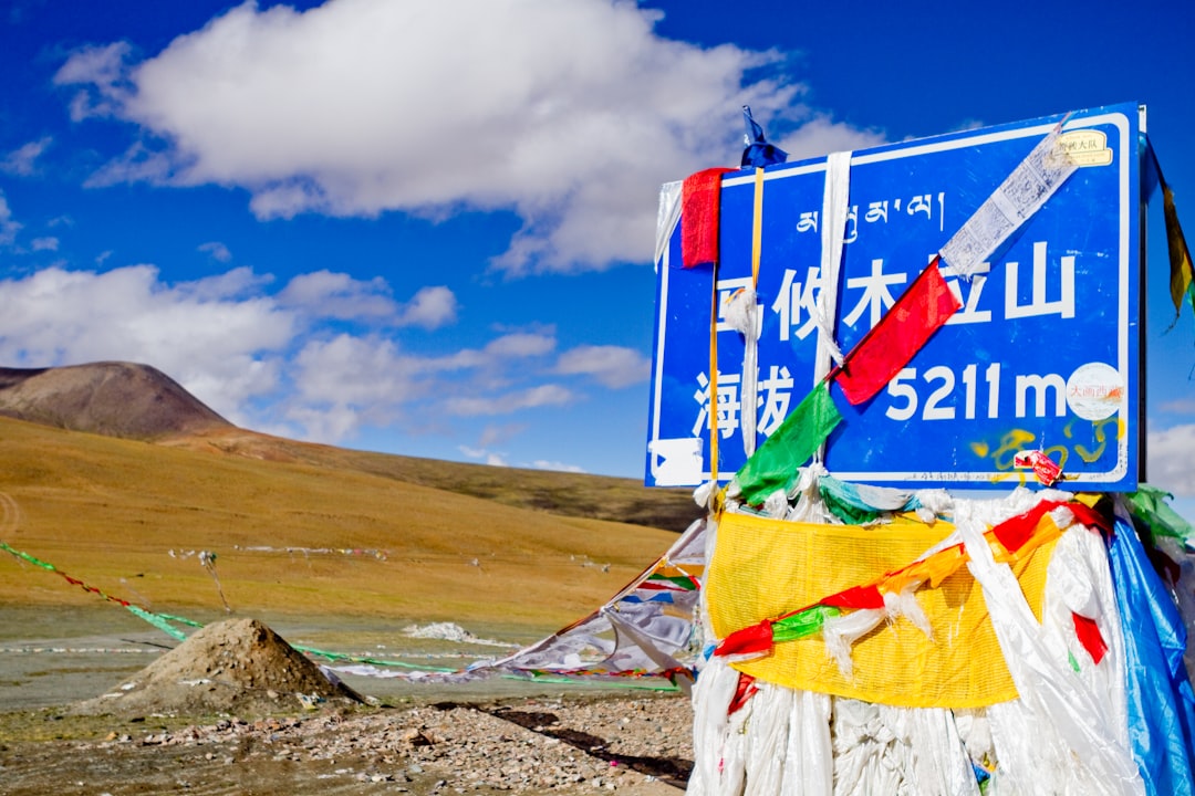 blue and white wooden signage on gray sand under blue sky during daytime