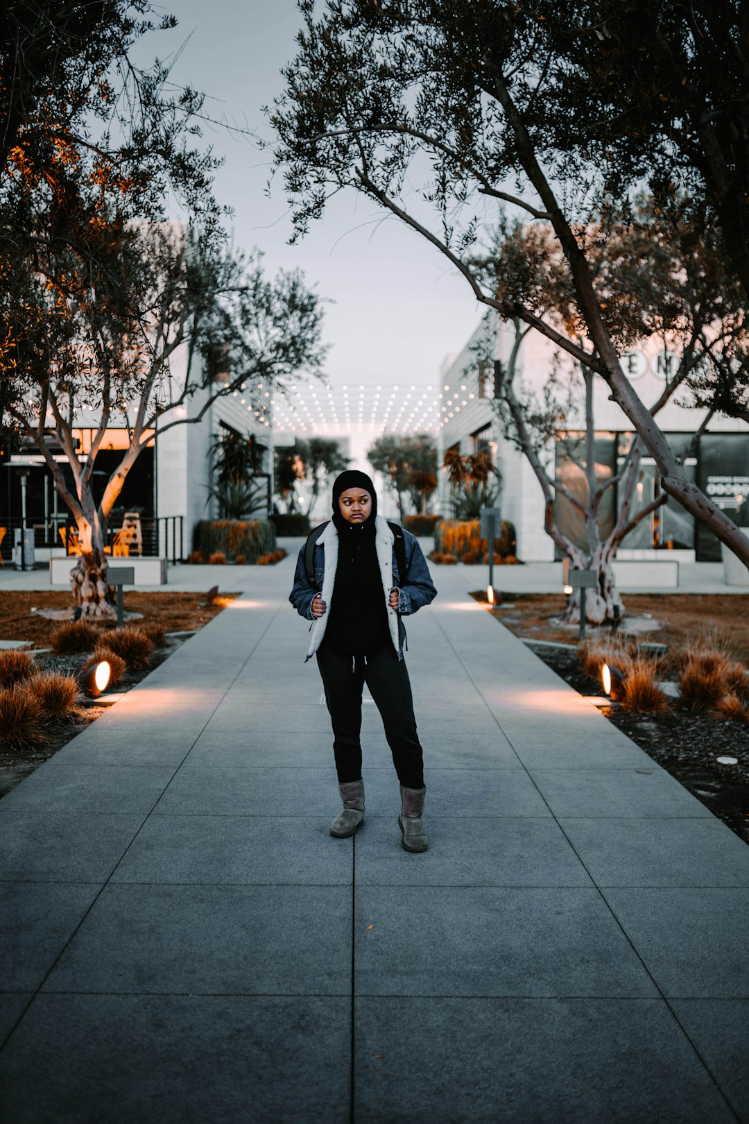 woman in black jacket standing on gray concrete pathway during daytime