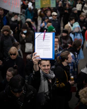 A friendly volunteer at a community event holding a clipboard and smiling warmly.
