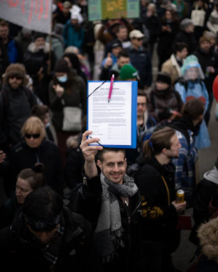 A friendly volunteer at a community event holding a clipboard and smiling warmly.