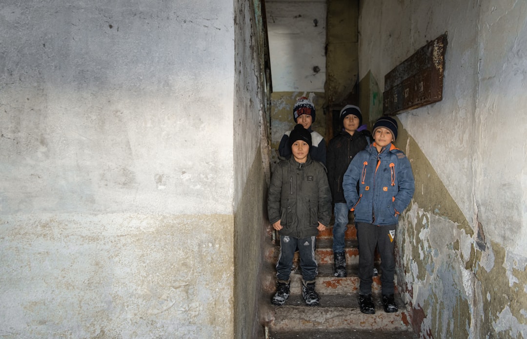 3 men in blue jacket standing beside white wall