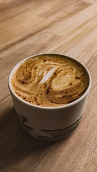 A vibrant ceramic mug with playful patterns, surrounded by coffee beans and a steaming cup of espresso.