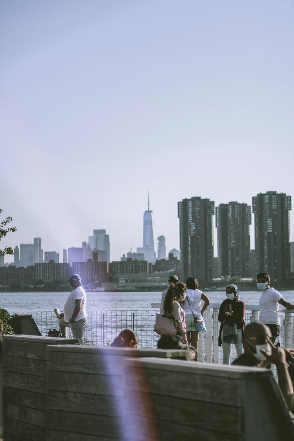 people standing on the bridge near the city during daytime